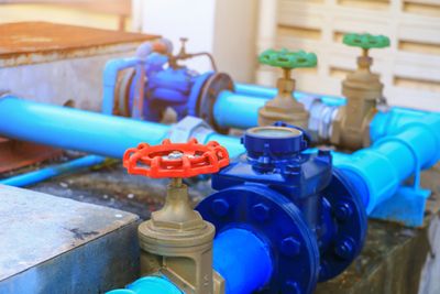 Blue water pipes with red and green valve handles in an industrial setting.