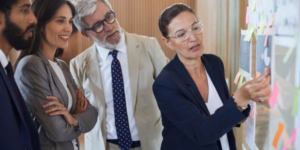 A group of professionals discussing ideas on a board with sticky notes.