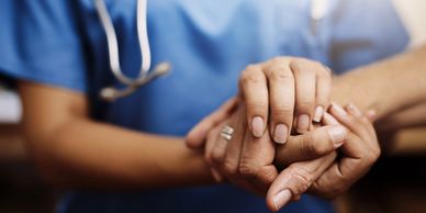 Nurse holding elderly patient's hand.
