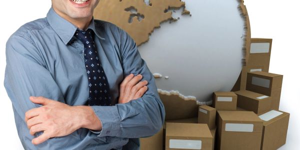 Smiling man with crossed arms and cardboard boxes.