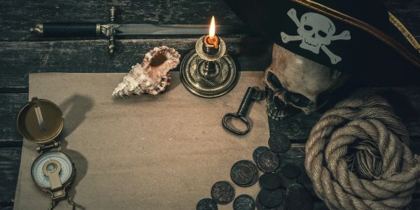 Pirate-themed scene with skull, coins, candle, and compass on wooden surface.