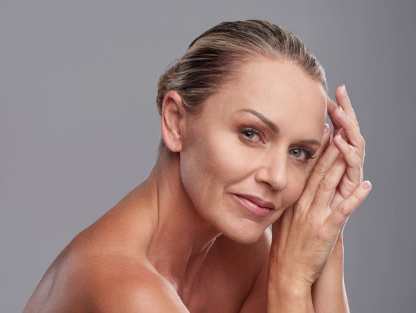 Mature woman gently resting her face on her hands with a serene expression.