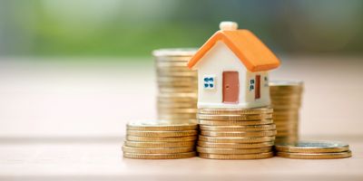 Miniature house on stacks of coins.