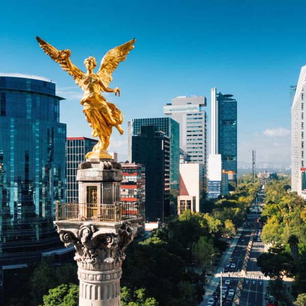 Golden Angel of Independence statue overlooking a busy urban avenue in Mexico City.
