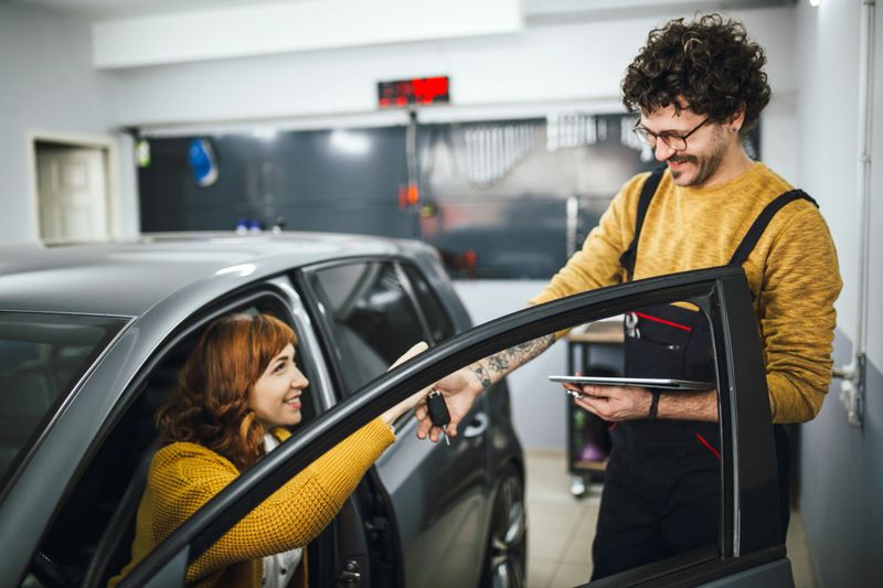 Repairman solving the car problems with a female customer in the car workshop