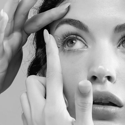 Close-up of a woman placing a contact lens in her eye.