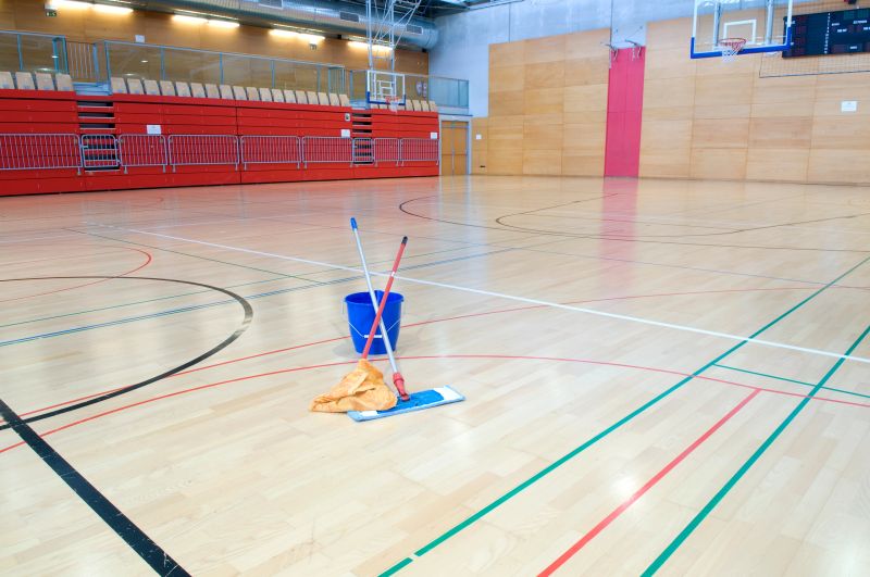 Floor Cleaning utensils on parquet of a big sports hall with red stand. Different colored lines lines on the floor define the court for different sports.