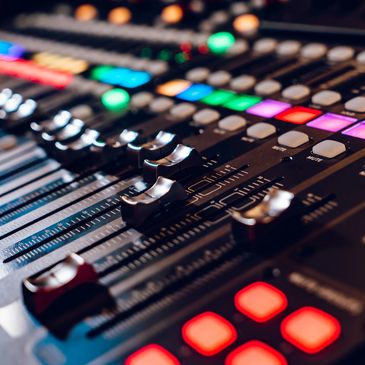 Close-up of a colorful audio mixing console with sliders and buttons ready to take on parties, weddings, and events of all kinds