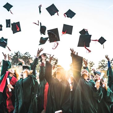 Graduates celebrating by throwing caps in the air.