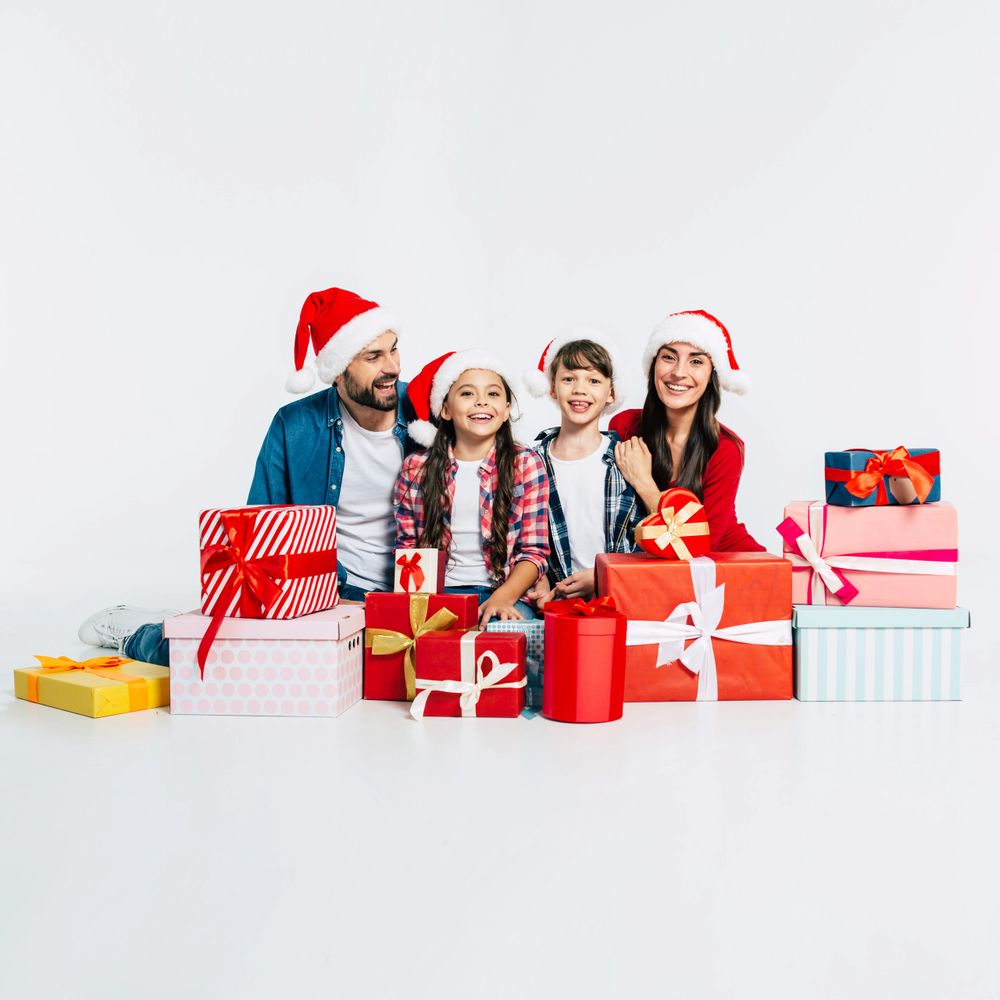 A happy family wearing Santa hats surrounded by Christmas gifts.