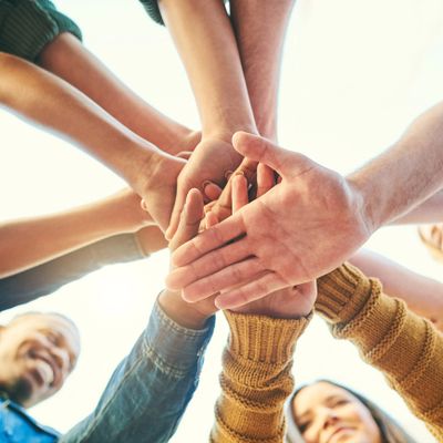 A group of diverse people stacking their hands together in unity.