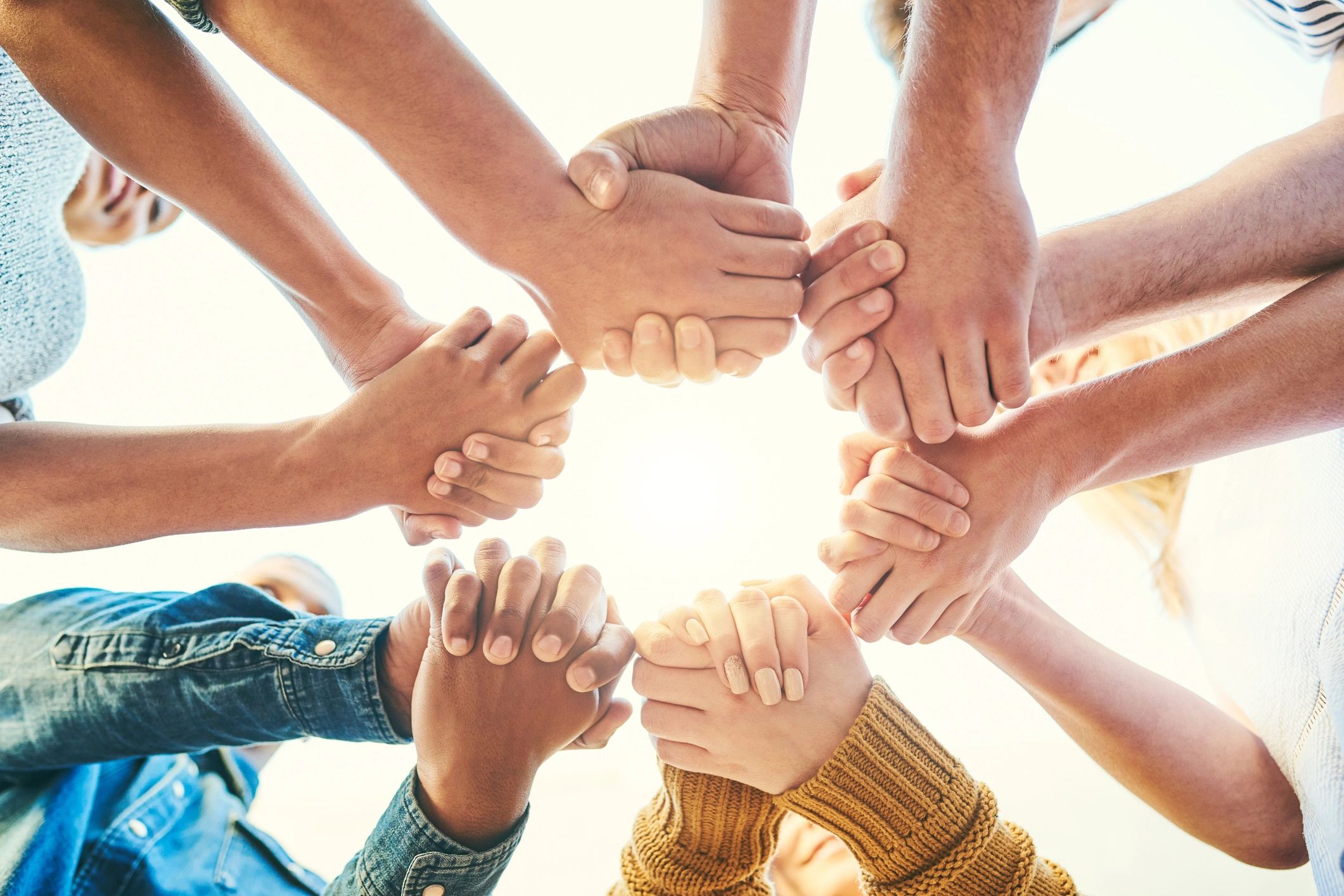 A diverse group holding hands in a circle symbolizing unity and support.