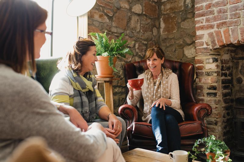 Small group of mature female friends sitting in a small coffee shop enjoying a catch up and a coffee.