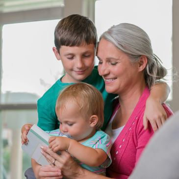 A grandmother reading a book to her grandchildren indoors.