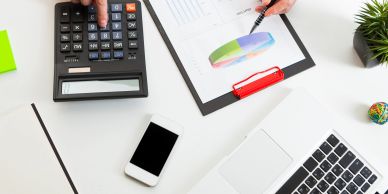 Workspace with calculator, smartphone, laptop, and pie chart analysis.