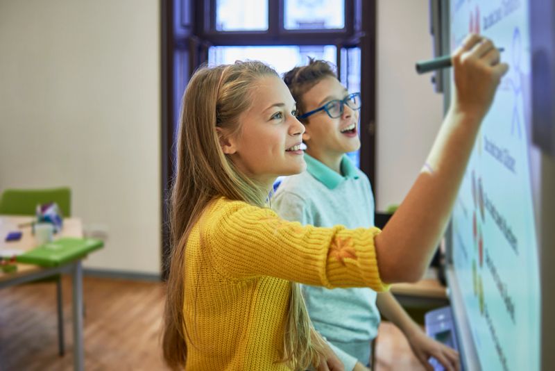 two school friends using the smart board for their project