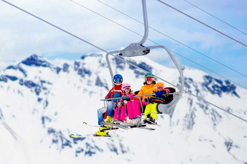 Family in ski lift in Swiss Alps mountains. Skiing with young kids. Father, mother and children sitting in ski lift during Christmas vacation. Winter outdoor sports for active family.