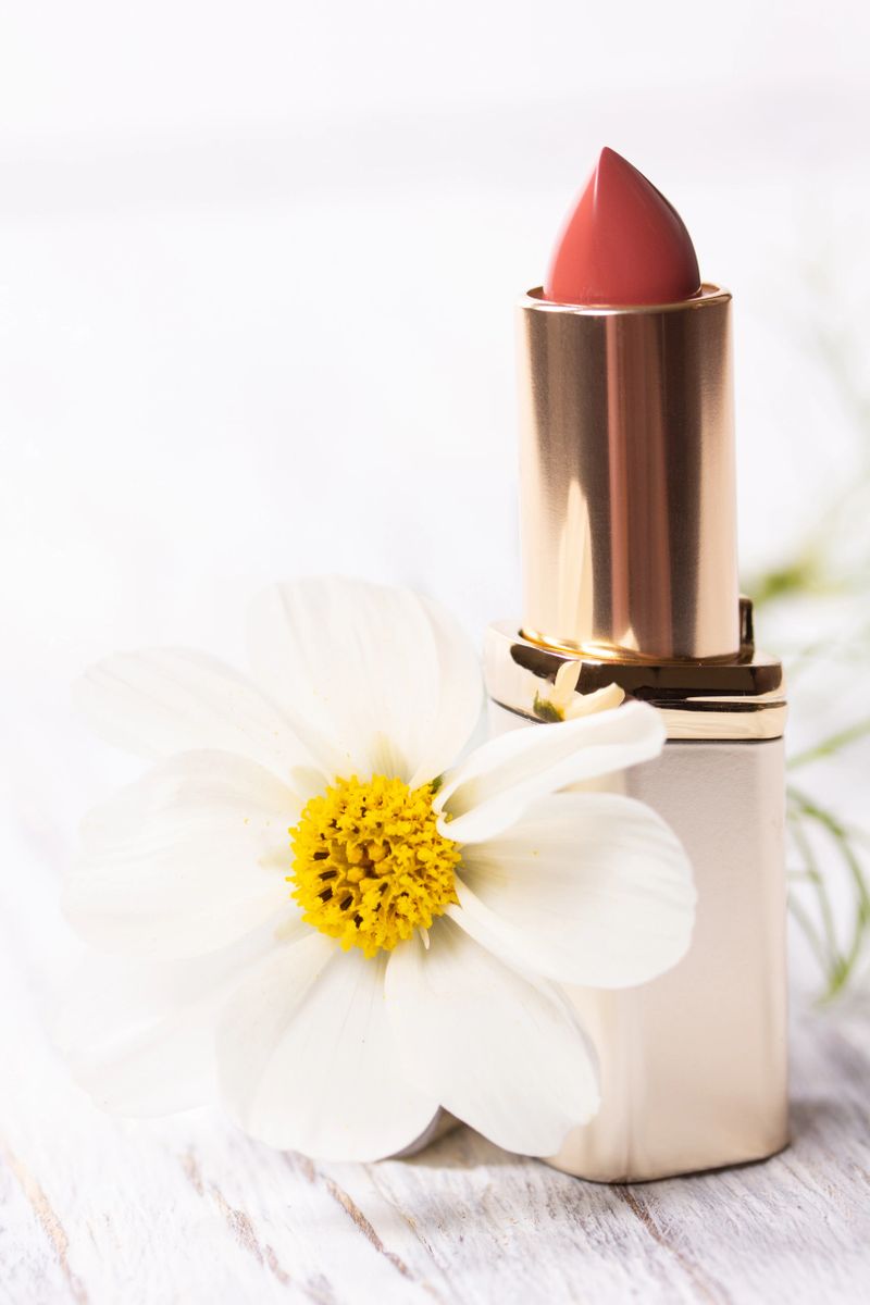 Lipstick and white flower on an old shabby wooden background