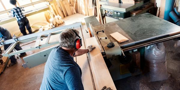 Man wearing ear protection working with wood in a workshop.
