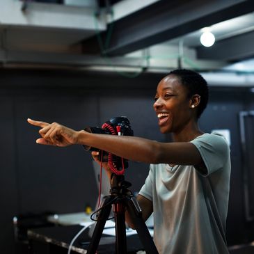Joyful person pointing while filming with a camera.