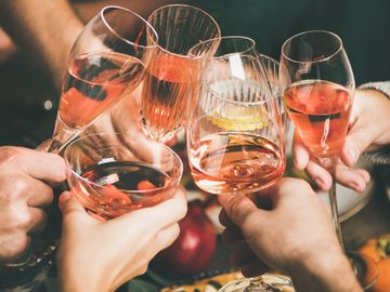 Friends clinking glasses filled with rosé wine in celebration.