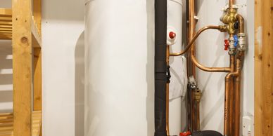 A domestic hot water cylinder with copper pipes and insulation in a utility room.