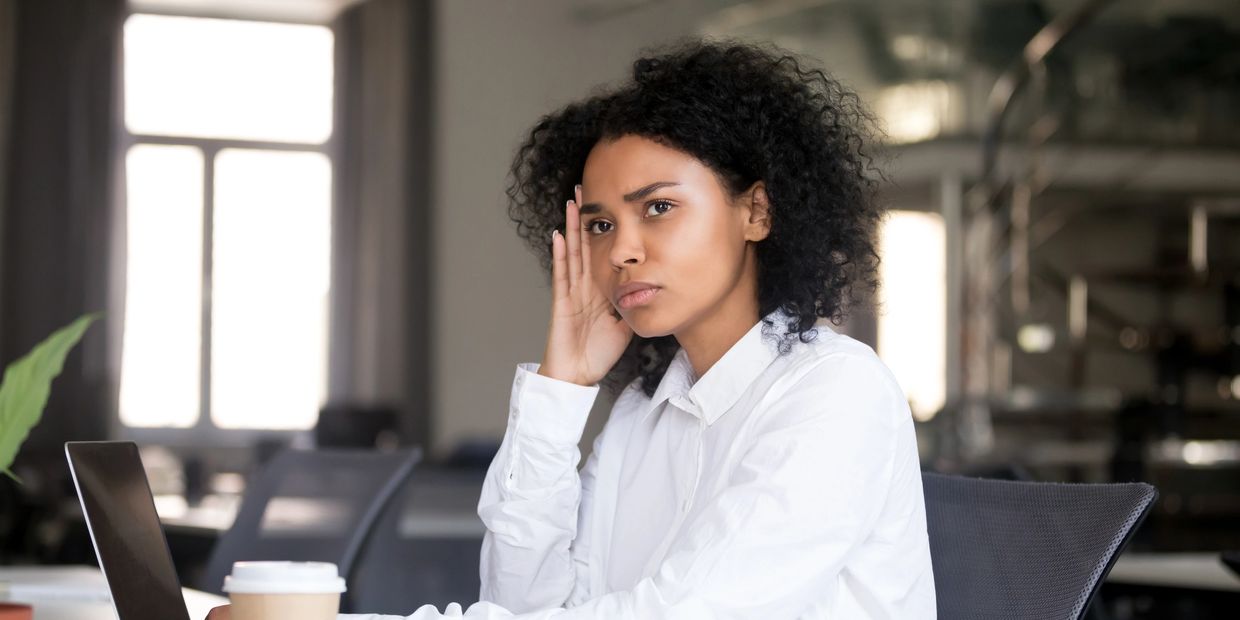 A woman sitting in an office, appearing distracted and unfocused, representing ADHD.