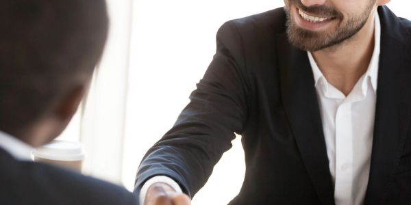 Two people shaking hands in a business setting.