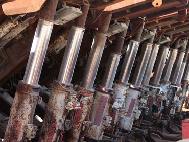 Row of rusted hydraulic pistons in an industrial machine.