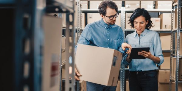 Two warehouse workers discussing inventory using a tablet.