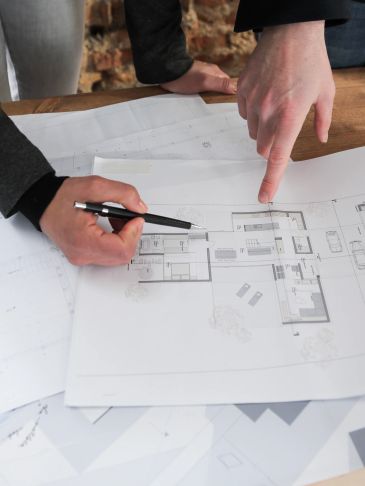 Two people reviewing architectural blueprints on a table.