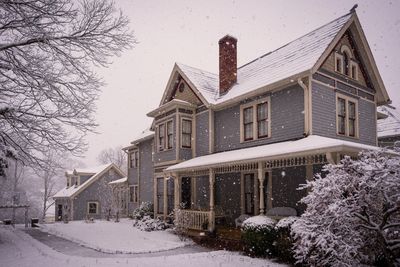 Victorian-style house covered in snow during a gentle snowfall.