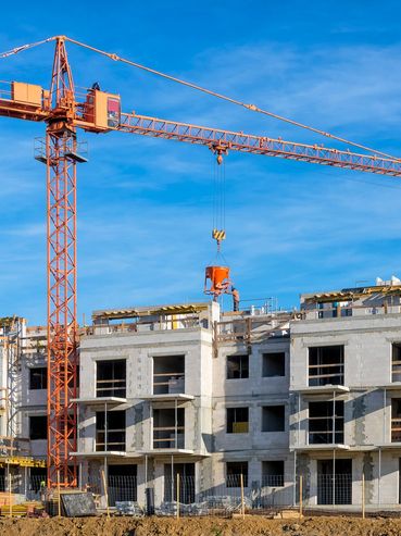A construction site with a crane and workers building a large concrete structure.
