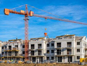 Construction site with crane and workers on building.
