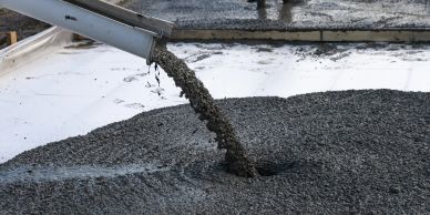 Wet concrete being poured onto a surface from a chute.