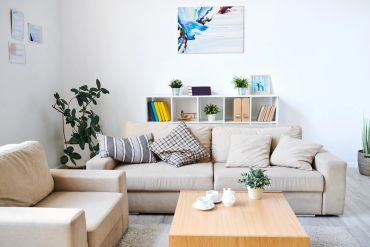 Cozy beige living room with sofa, armchair, coffee table, and plants.