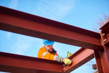 Worker in safety gear assembling steel beams.