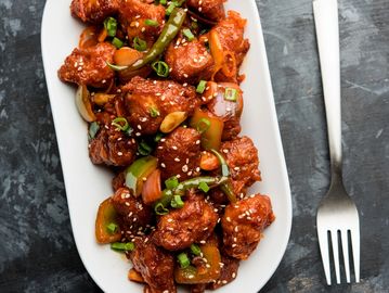 Spicy Indo-Chinese chili chicken garnished with sesame seeds and spring onions.