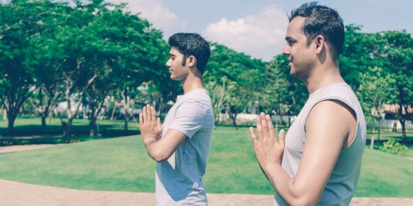 Two young men practicing yoga outdoors in a peaceful park.