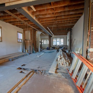 Interior of a house under renovation with exposed beams and construction materials.
