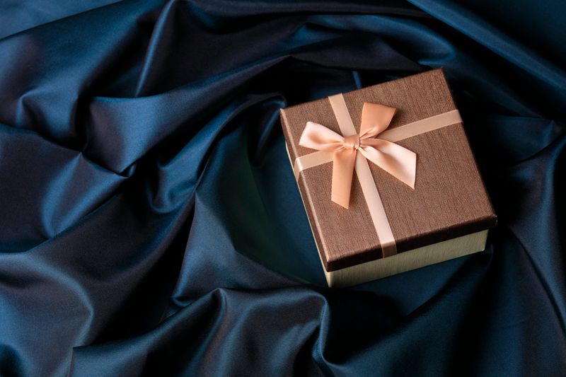 Golden gift box on navy blue satin background