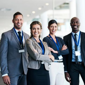 A diverse group of four business professionals smiling confidently.