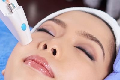 A woman receiving a facial skin treatment with a device.