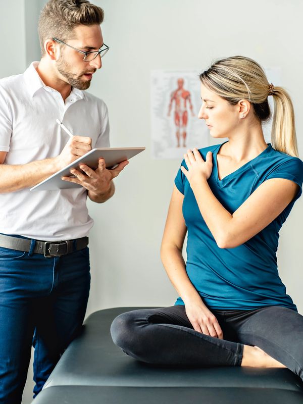 Physical therapist assessing woman's shoulder pain during consultation.