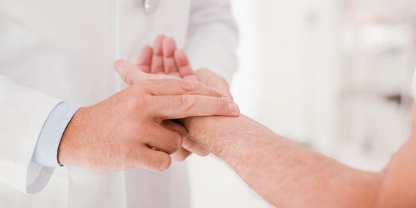 Doctor checking patient's pulse on wrist in a clinical setting.