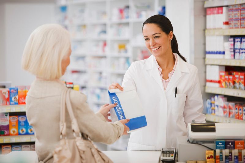 Pharmacist handing customer prescription in drug store