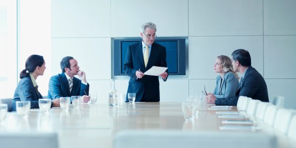 Business meeting with a man presenting to colleagues around a conference table.