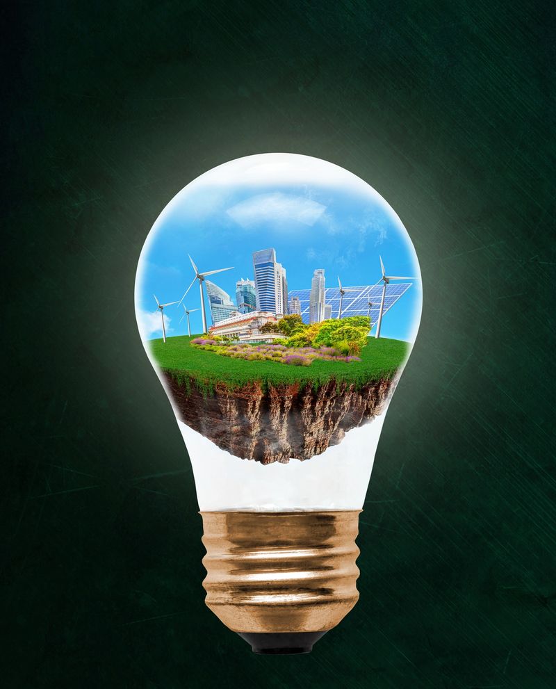 Floating city inside light bulb with renewable energy symbols of wind turbines and solar panels. Concept of eco-friendly, energy efficient city and idea of environmental conservation in modern green city. Image composed of photos taken separately, reference images attached.