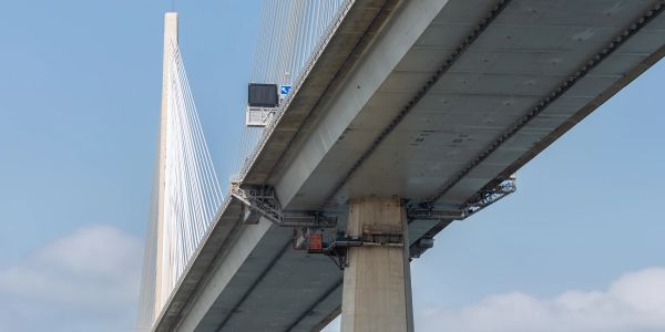 View from below of a modern cable-stayed bridge against a blue sky.
