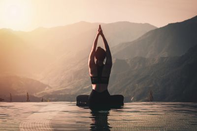 Person doing yoga by the water at sunrise.